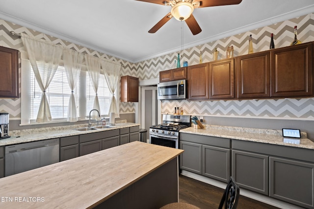 kitchen with wallpapered walls, ornamental molding, appliances with stainless steel finishes, and a sink