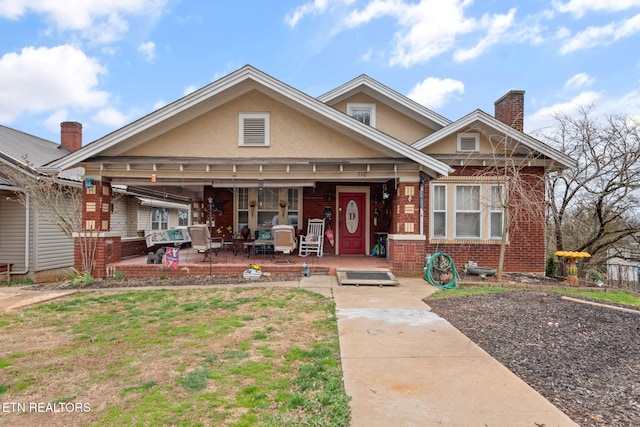 view of front of property featuring a patio, stucco siding, brick siding, and a chimney