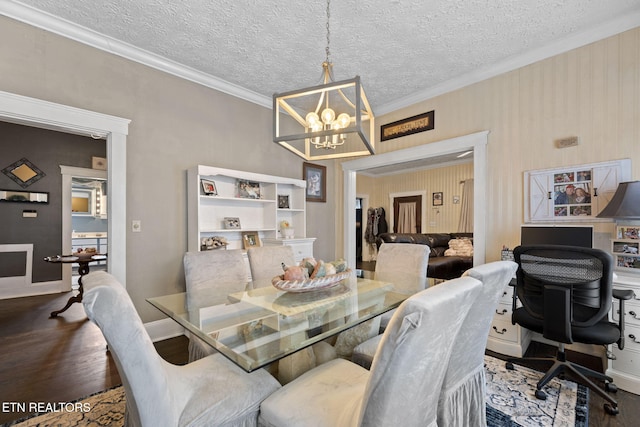 dining area featuring a textured ceiling, ornamental molding, wood finished floors, and a chandelier