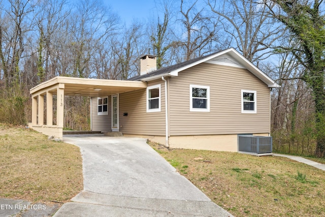 view of front of property featuring a carport, concrete driveway, a front lawn, and a chimney