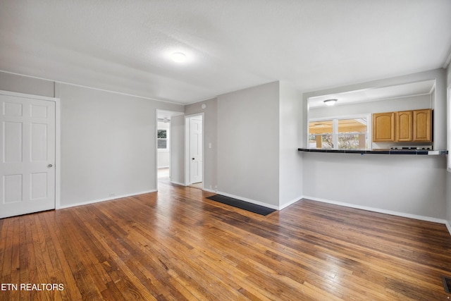 unfurnished living room with a healthy amount of sunlight, baseboards, and hardwood / wood-style flooring