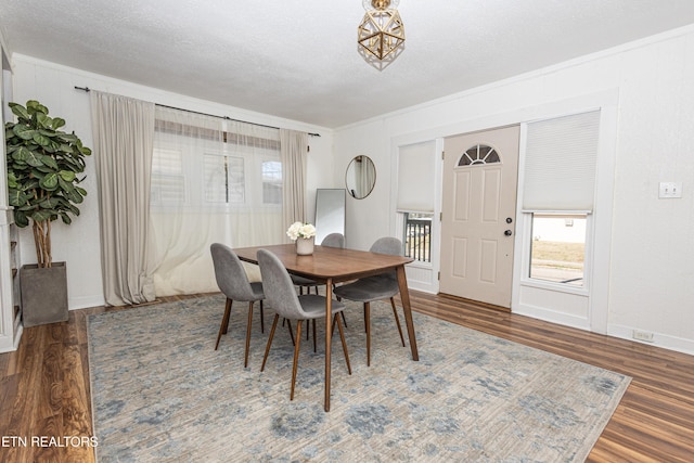 dining area featuring a textured ceiling, baseboards, and wood finished floors