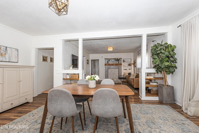 dining space with a textured ceiling, dark wood-style flooring, and crown molding