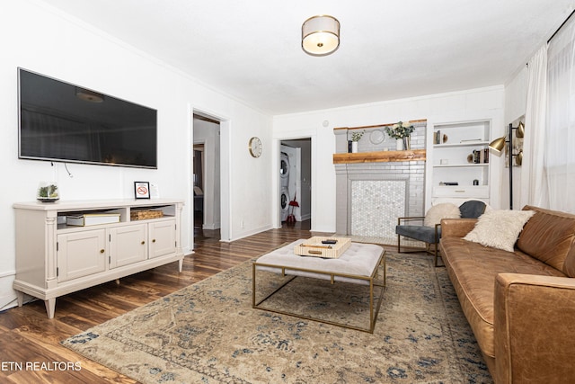 living room featuring built in features, baseboards, dark wood finished floors, and crown molding