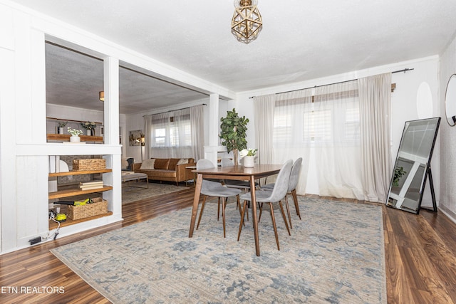 dining space with a textured ceiling and wood finished floors