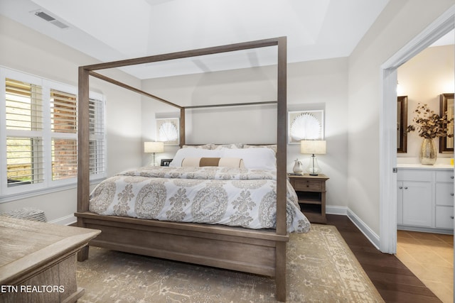 bedroom featuring visible vents, connected bathroom, baseboards, and dark wood-style flooring