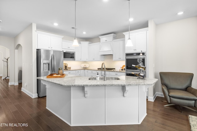 kitchen with a sink, stainless steel appliances, arched walkways, and white cabinets