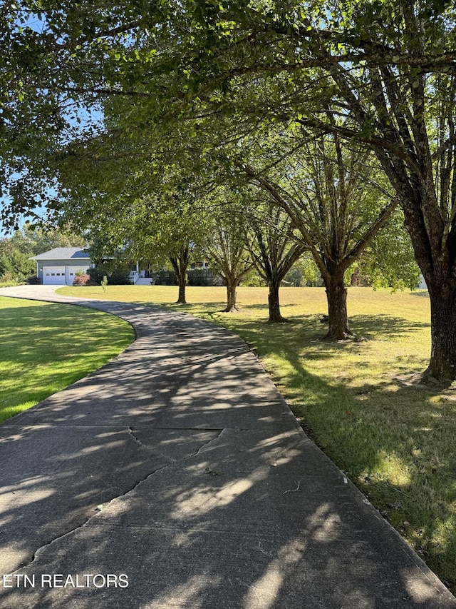 view of property's community with a yard, a garage, and driveway