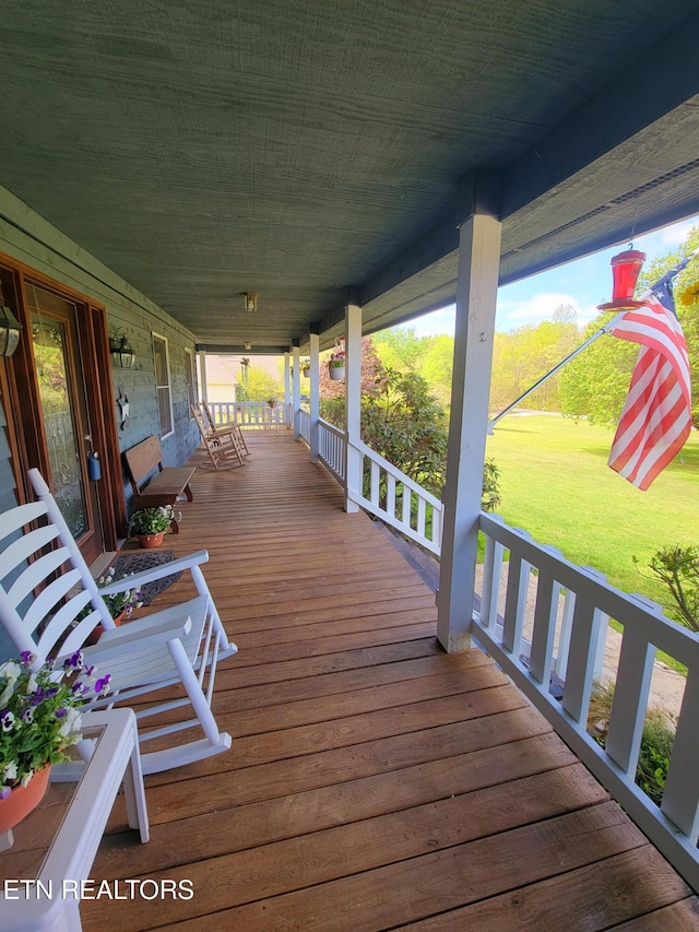 wooden terrace featuring a porch and a yard