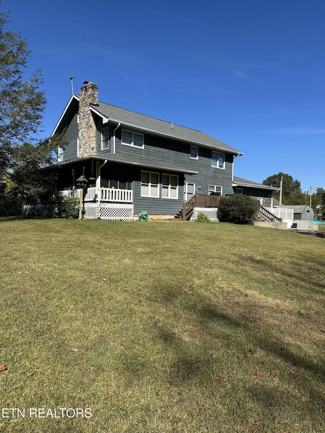 back of house with a yard and a chimney