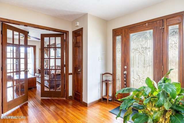 entryway with light wood-style flooring, french doors, and baseboards