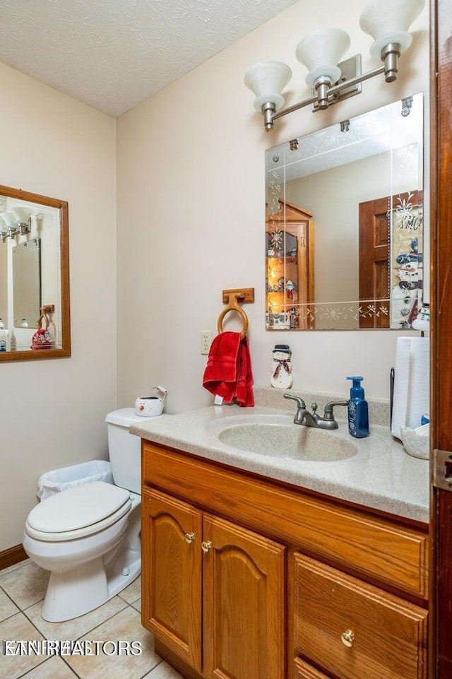 bathroom featuring tile patterned flooring, toilet, vanity, and a textured ceiling