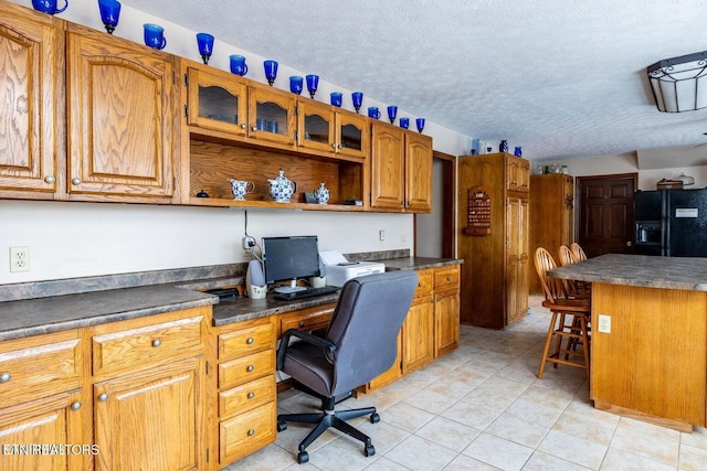 home office featuring light tile patterned floors, a textured ceiling, and built in desk