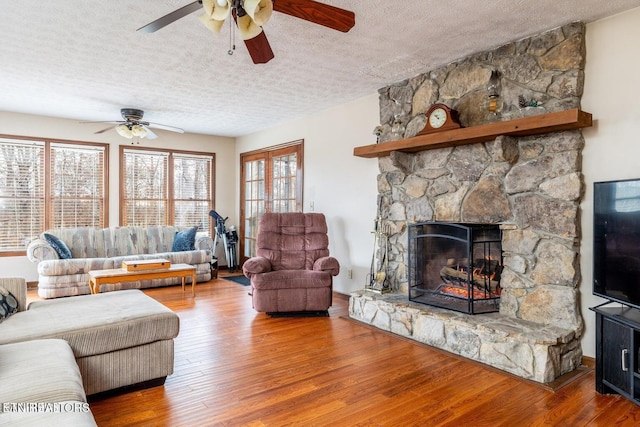 living area featuring a fireplace, wood finished floors, and a textured ceiling