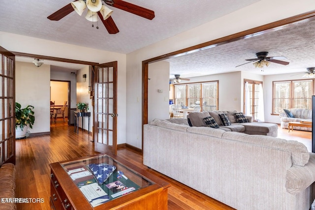 living area with french doors, a textured ceiling, baseboards, and hardwood / wood-style floors