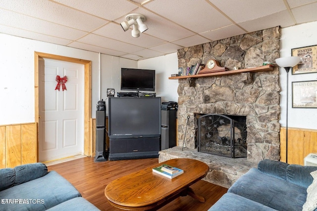 living area with a drop ceiling, wainscoting, a fireplace, and wood finished floors