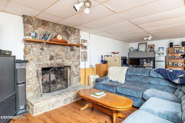 living area with a drop ceiling, a fireplace, and wood finished floors