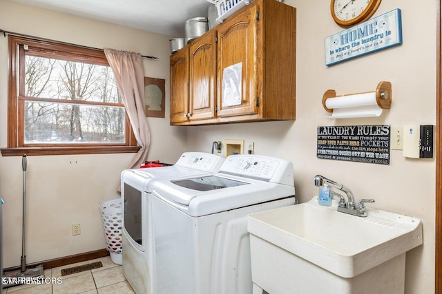 clothes washing area featuring visible vents, separate washer and dryer, light tile patterned flooring, cabinet space, and a sink