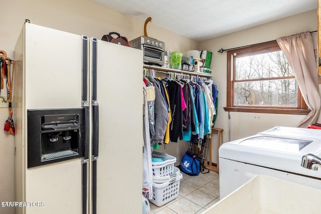 laundry area with light tile patterned floors, laundry area, washing machine and dryer, and a textured ceiling