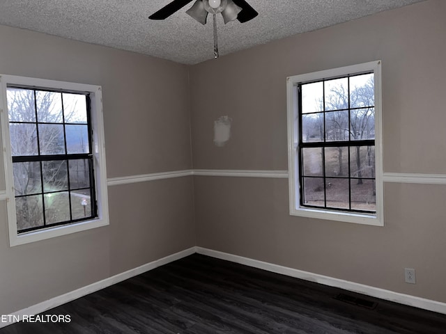 spare room featuring visible vents, baseboards, dark wood-style floors, a textured ceiling, and a ceiling fan