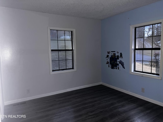 unfurnished room with visible vents, baseboards, dark wood-style flooring, and a textured ceiling