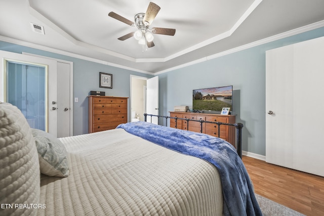 bedroom featuring a tray ceiling, crown molding, and wood finished floors