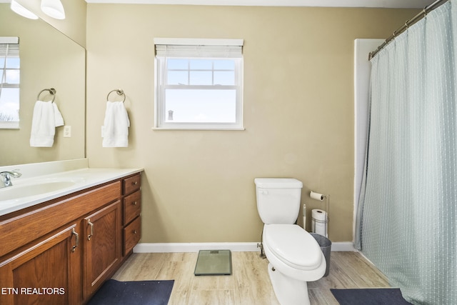 bathroom featuring baseboards, toilet, wood finished floors, and vanity