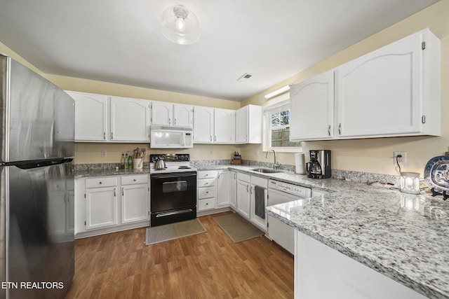 kitchen with light stone countertops, light wood-style floors, white cabinets, white appliances, and a sink