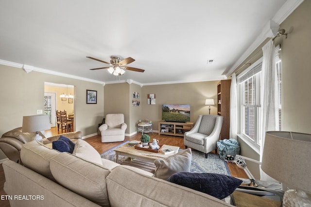 living room featuring visible vents, crown molding, baseboards, ceiling fan with notable chandelier, and wood finished floors