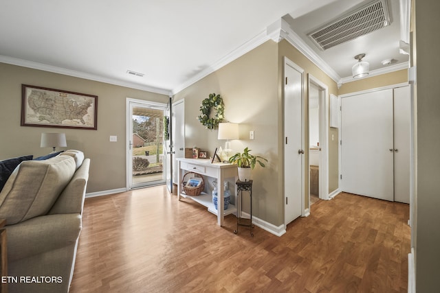 interior space featuring visible vents, baseboards, wood finished floors, and crown molding