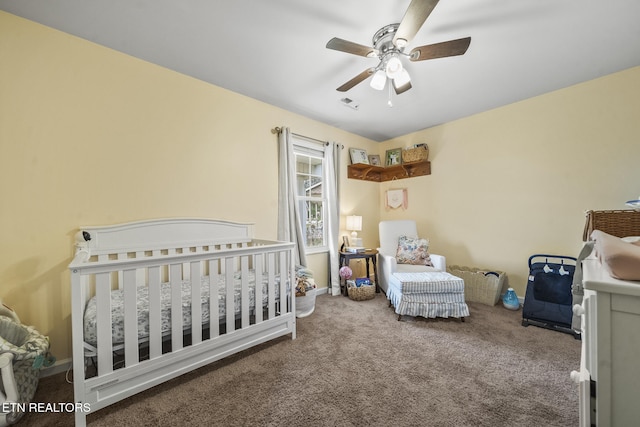 bedroom with visible vents, a crib, baseboards, carpet flooring, and a ceiling fan