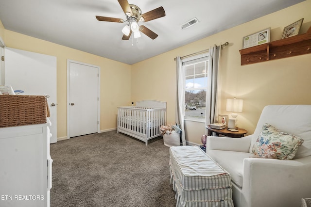 carpeted bedroom featuring a crib, baseboards, visible vents, and ceiling fan