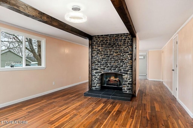 unfurnished living room with a stone fireplace, beam ceiling, hardwood / wood-style flooring, and baseboards