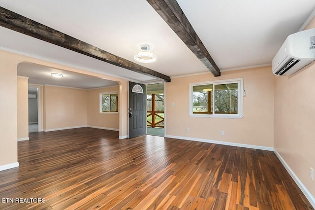 spare room with a wall mounted air conditioner, baseboards, and beam ceiling