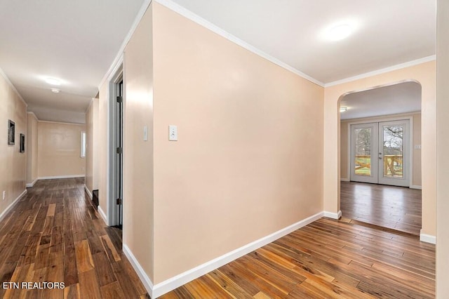 hall with baseboards, arched walkways, ornamental molding, dark wood-type flooring, and french doors