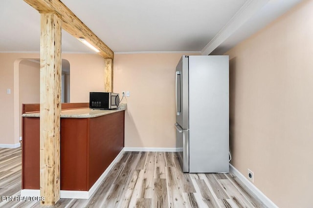 kitchen with ornamental molding, light wood-style floors, appliances with stainless steel finishes, light countertops, and baseboards