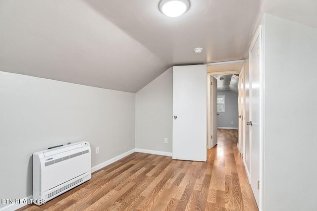 bonus room with baseboards, heating unit, lofted ceiling, and light wood-style flooring