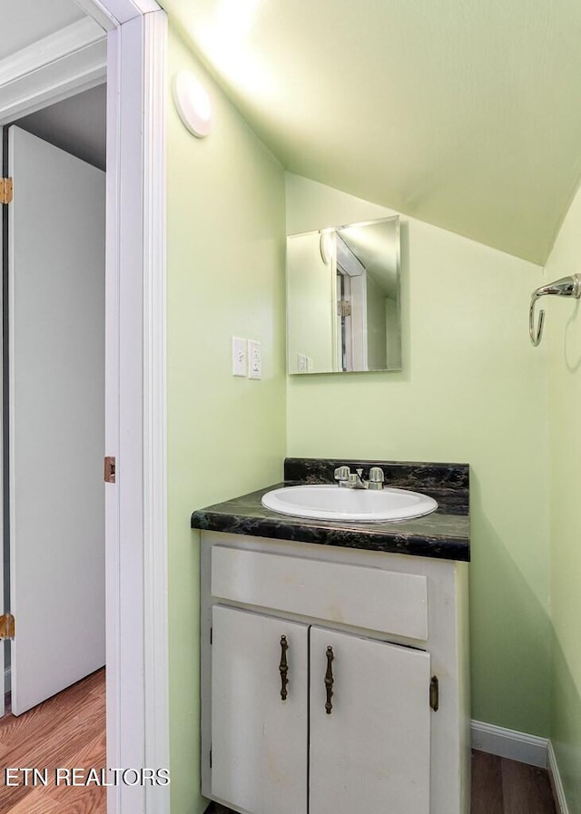 bathroom with vanity, lofted ceiling, wood finished floors, and baseboards