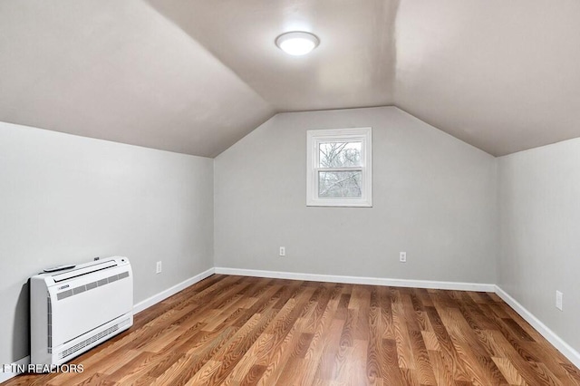 additional living space featuring baseboards, heating unit, wood finished floors, and vaulted ceiling