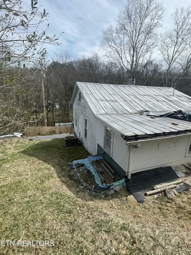 view of property exterior with metal roof, a lawn, central AC unit, and entry steps