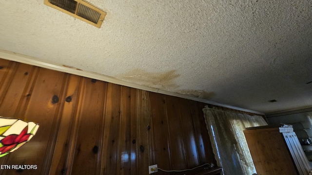 room details with visible vents, wooden walls, and a textured ceiling