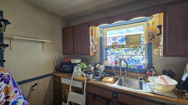 kitchen featuring wainscoting, black microwave, and a sink