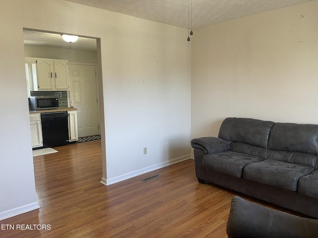 living area featuring baseboards, dark wood-style flooring, and a textured ceiling