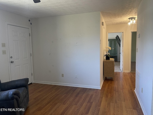 living area featuring wood finished floors, baseboards, and a textured ceiling