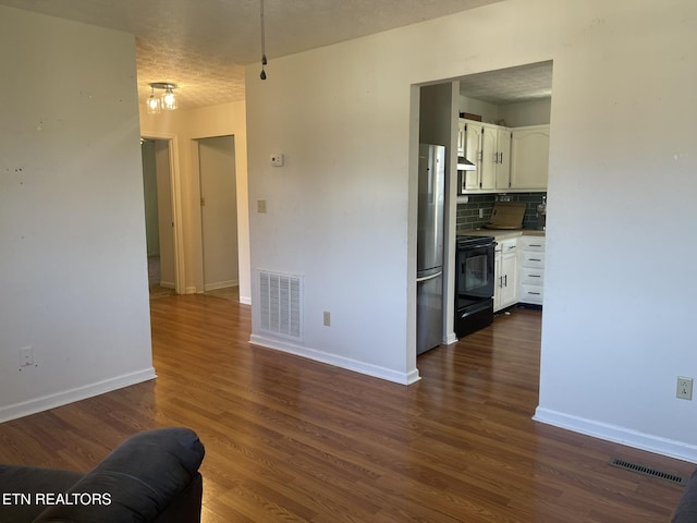 unfurnished living room featuring dark wood finished floors, baseboards, visible vents, and a textured ceiling