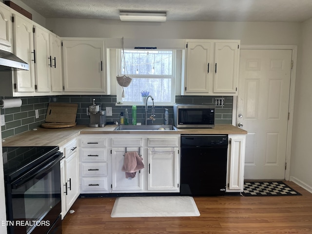 kitchen featuring a sink, black appliances, dark wood-style flooring, and white cabinetry