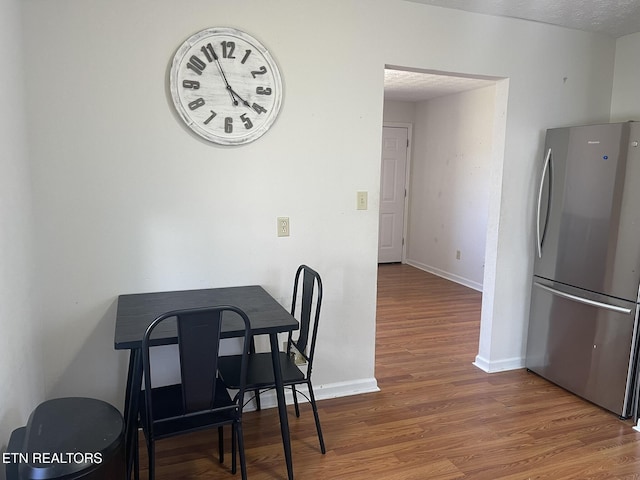 dining room featuring baseboards, a textured ceiling, and wood finished floors