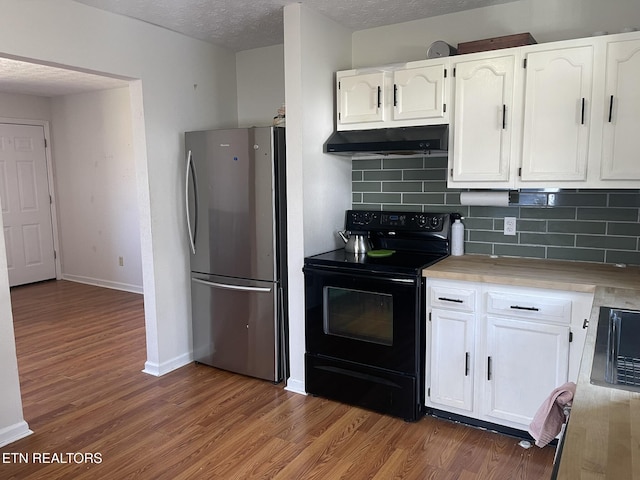 kitchen with black range with electric stovetop, under cabinet range hood, wood finished floors, white cabinetry, and freestanding refrigerator