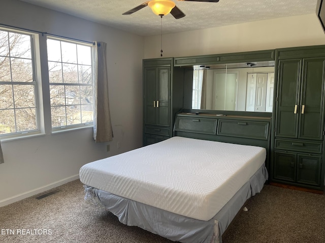 bedroom featuring visible vents, a ceiling fan, a textured ceiling, carpet floors, and baseboards