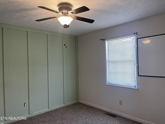 carpeted spare room featuring baseboards, visible vents, and a textured ceiling